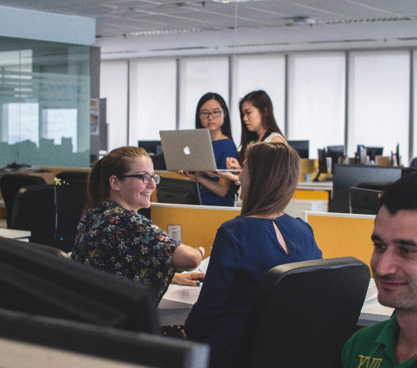 Team of professionals collaborating in a modern office environment, representing the cross-functional teamwork and operational efficiency supported by Revenue Nomad’s enablement solutions.